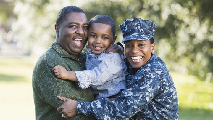 Black veteran hugging his wife and toddler son